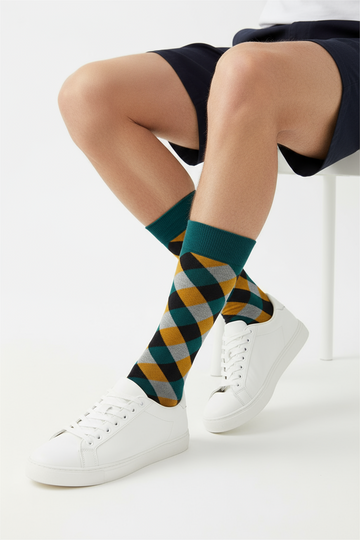 Person wearing colorful argyle socks with white sneakers on a light background
