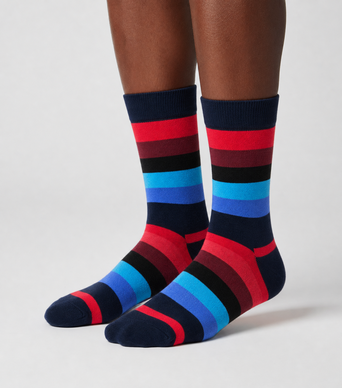 A pair of crew socks with bold horizontal stripes in navy, red, black, burgundy, blue, and light blue, shown on a model&
