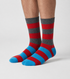 A pair of crew socks with a colorful geometric block pattern in green, blue, red, yellow, black, and white, worn on a person&